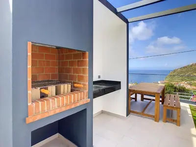 an outdoor kitchen with a view of the ocean at Noah - Private Sunset Hideaway by LovelyStay in Arco da Calheta