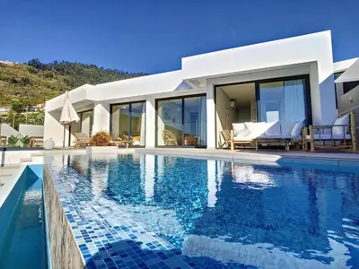 a villa with a swimming pool in front of a house at Noah - Private Sunset Hideaway by LovelyStay in Arco da Calheta