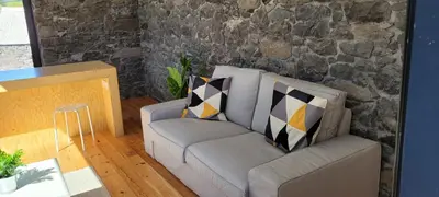 a living room with a couch and a stone wall at House Nobrega of Madeira in Arco da Calheta