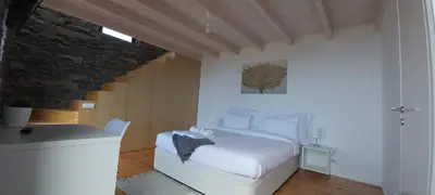 a bedroom with a white bed and a staircase at House Nobrega of Madeira in Arco da Calheta
