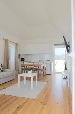 a white living room with a table and a kitchen at House Nobrega of Madeira in Arco da Calheta