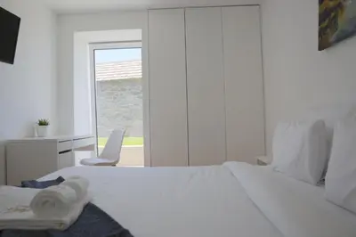 a white bedroom with a white bed and a window at House Nobrega of Madeira in Arco da Calheta