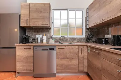 a kitchen with wooden cabinets and a stainless steel dishwasher at CASA POR DO SOL in Calheta