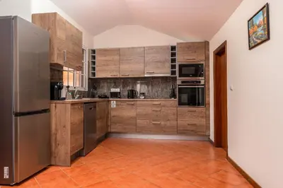 a kitchen with wooden cabinets and stainless steel appliances at CASA POR DO SOL in Calheta