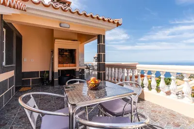 a patio with a table and chairs on a balcony at CASA POR DO SOL in Calheta