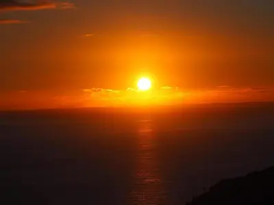 a sunset over the ocean with the sun in the sky at CASA POR DO SOL in Calheta