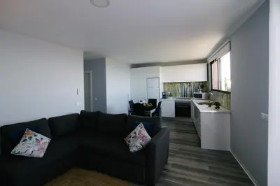 a living room with a black couch and a kitchen at Casa do Brasileiro in Arco da Calheta