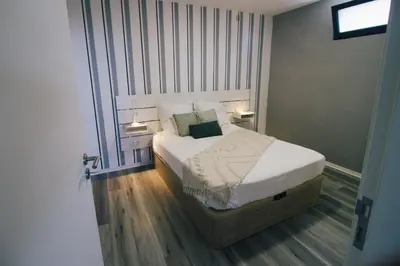 a bedroom with a bed with white sheets and pillows at Casa do Brasileiro in Arco da Calheta