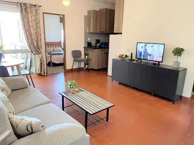 a living room with a couch and a tv and a table at Apartamento vista mar e pôr do Sol (1,6km Praia) in Aljezur