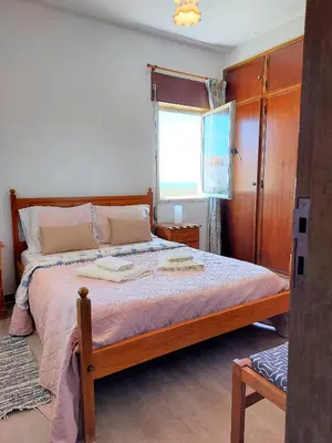 a bedroom with a bed with a wooden frame and a window at Apartamento vista mar e pôr do Sol (1,6km Praia) in Aljezur