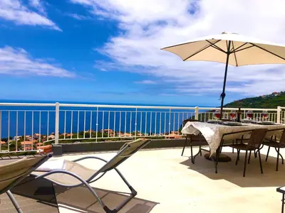 a grill on a balcony with a view of the ocean at Casa Neves three bedrooms and fantastic sea view in Arco da Calheta
