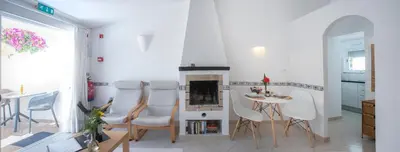 a living room with a fireplace and a table and chairs at Cozy Studio with garden view in Praia da Luz in Luz