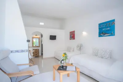 a white living room with a white couch and a table at Cozy Studio with garden view in Praia da Luz in Luz