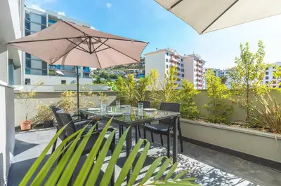 a table and chairs with an umbrella on a balcony at Terrace Apartment by Atlantic Holiday in Funchal