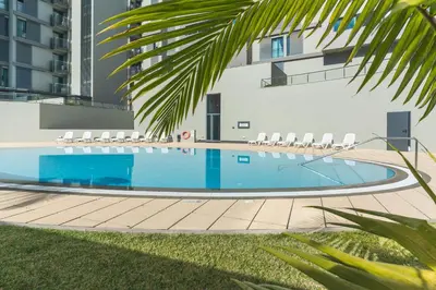 a swimming pool with chairs and a building at Terrace Apartment by Atlantic Holiday in Funchal