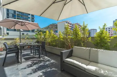 a patio with a couch and a table and umbrella at Terrace Apartment by Atlantic Holiday in Funchal