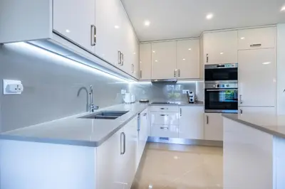 a white kitchen with white cabinets and appliances at Casa Malhotra at Boa Vista Golf Resort, Bayview Village in Lagos