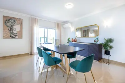 a dining room with a black table and green chairs at Casa Malhotra at Boa Vista Golf Resort, Bayview Village in Lagos
