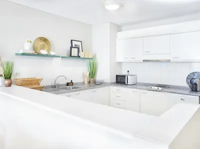 a white kitchen with white cabinets and a microwave at Lovely apartment with pool and sea view in Funchal