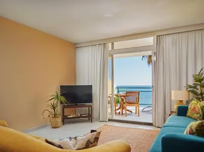 a living room with a couch and a television and a balcony at Lovely apartment with pool and sea view in Funchal