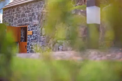 a stone building with a wooden door in the grass at Palheiros do Serrado by Real Vision in Estreito da Calheta