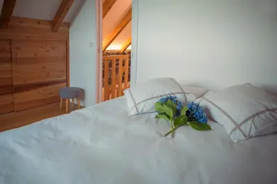 a white bed with a bouquet of blue flowers on it at Palheiros do Serrado by Real Vision in Estreito da Calheta