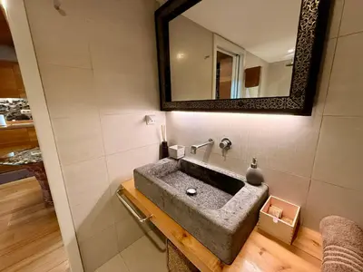 a bathroom with a stone sink and a mirror at Palheiros do Serrado by Real Vision in Estreito da Calheta