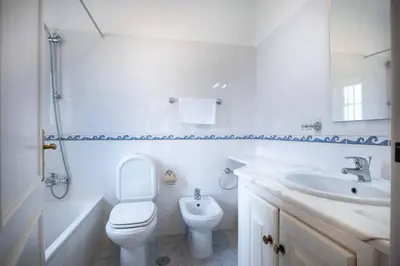 a white bathroom with a toilet and a sink at Villa Estrella - Praia da Luz in Luz
