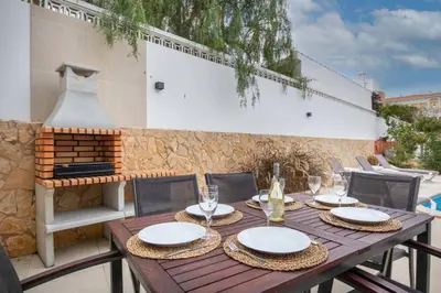 a wooden table with plates and wine glasses on a patio at Villa Estrella - Praia da Luz in Luz
