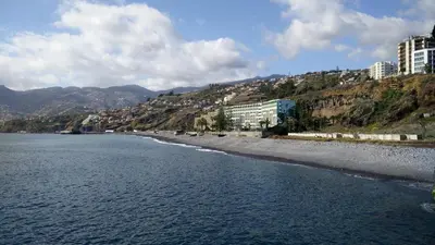 a view of a beach with buildings and mountains at Tranquil Beachside Stay - Atlantic Gardens Beach in Funchal