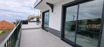 a balcony with glass doors and a view of a city at Villa Castanho I in Calheta