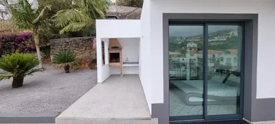 a white house with a balcony with a bed at Villa Castanho I in Calheta