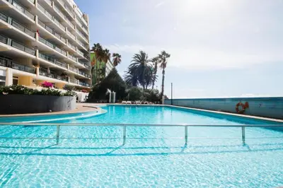 a large swimming pool next to a large building at Atlantic Gardens Beach - atlanticgardensbeach com in Funchal