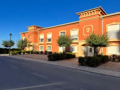 an orange building with trees in front of a street at Fairway 3 Apartment - Boavista Golf & Spa Resort in Lagos