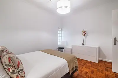 a white bedroom with a bed and a vase on a dresser at Canico Sea Garden by Homie in Caniço