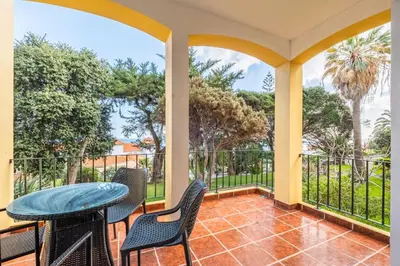 a balcony with a table and chairs and trees at Canico Sea Garden by Homie in Caniço