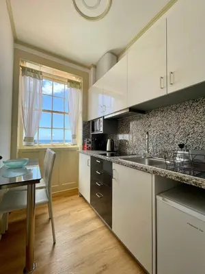 a kitchen with white cabinets and a table and a window at Carreira Apartments Harbour View Free Parking in Heart Funchal in Funchal