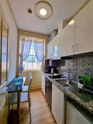 a kitchen with a table and a sink and a table and a window at Carreira Apartments Harbour View Free Parking in Heart Funchal in Funchal