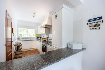 a kitchen with white cabinets and a black counter top at CoolHouses Luz, 3 Bed linked house, shared pool, a stone's throw of the sea, Casa Sirrah in Luz