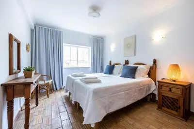 a bedroom with a large bed and a desk and a window at CoolHouses Luz, 3 Bed linked house, shared pool, a stone's throw of the sea, Casa Sirrah in Luz