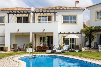 a villa with a swimming pool in front of a house at CoolHouses Luz, 3 Bed linked house, shared pool, a stone's throw of the sea, Casa Sirrah in Luz