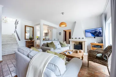a living room with a couch and a fireplace at CoolHouses Luz, 3 Bed linked house, shared pool, a stone's throw of the sea, Casa Sirrah in Luz