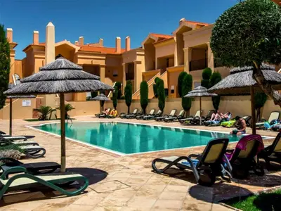 a swimming pool with chairs and umbrellas in a resort at Sunny Retreat in Luz