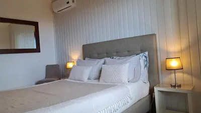 a bedroom with a bed with pillows and two lamps at Authentic Rural Retreat With Green Fields & Ocean Views - Orchid House Arco da Calheta in Calheta
