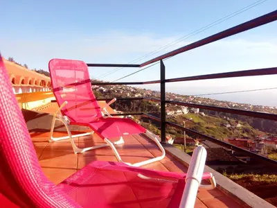 a balcony with pink chairs and a view of a city at Authentic Rural Retreat With Green Fields & Ocean Views - Orchid House Arco da Calheta in Calheta
