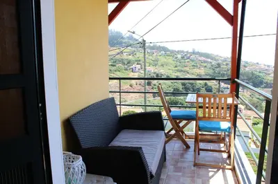 a balcony with a couch and a table and chairs at Authentic Rural Retreat With Green Fields & Ocean Views - Orchid House Arco da Calheta in Calheta