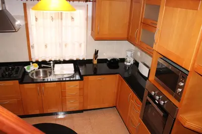 a small kitchen with wooden cabinets and a sink at Authentic Rural Retreat With Green Fields & Ocean Views - Orchid House Arco da Calheta in Calheta