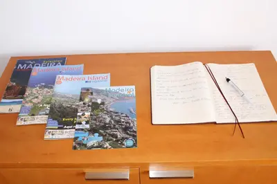 a desk with an open book and a pen and books at Authentic Rural Retreat With Green Fields & Ocean Views - Orchid House Arco da Calheta in Calheta