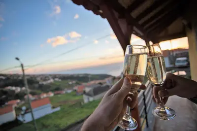 two people holding up wine glasses in front of a window at Authentic Rural Retreat With Green Fields & Ocean Views - Orchid House Arco da Calheta in Calheta