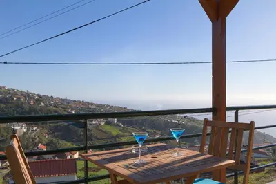 a wooden table with two blue glasses on it at Authentic Rural Retreat With Green Fields & Ocean Views - Orchid House Arco da Calheta in Calheta